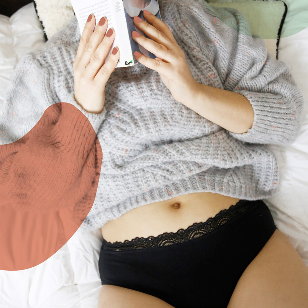 Femme allongée en culotte menstruelle avec un lire dans l a main